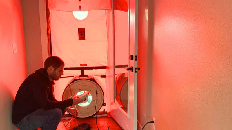 Energy Planner Paul Cutting crouches by blower door
