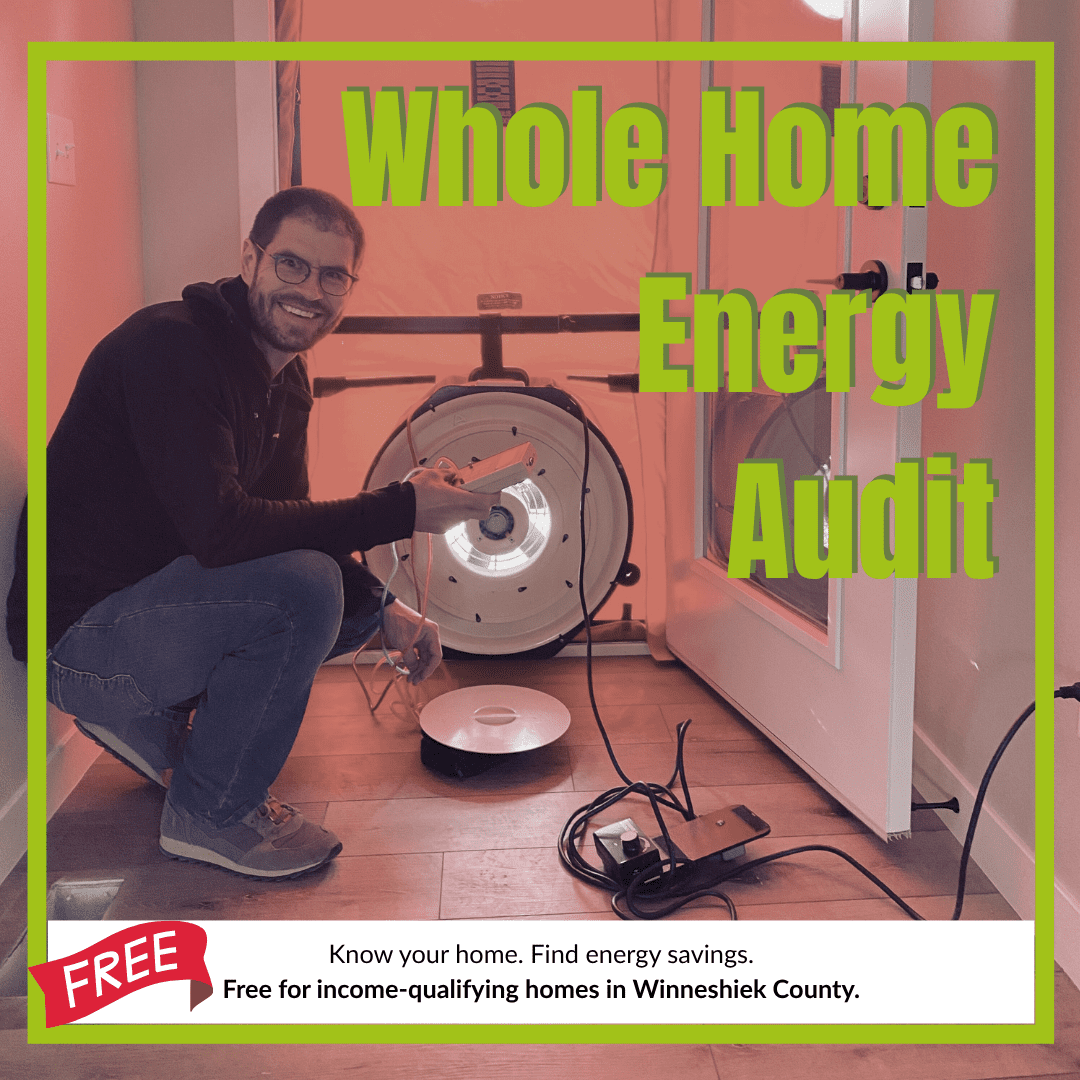 A man kneels next to a blower door test setup in a home, promoting a free whole home energy audit for income-qualifying residents in Winneshiek County.