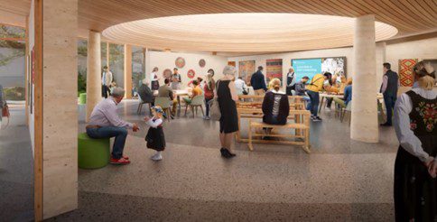 People are gathered in a spacious, modern room with wooden ceilings and large windows, engaging in conversation and activities at tables and benches.
