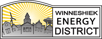 Logo for Winneshiek Energy District featuring a stylized town skyline with a wind turbine, sun rays, and bold text on a white and grey background.